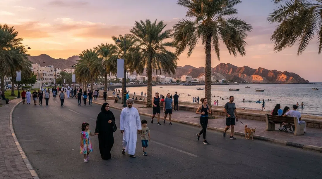 Playa de Qurum y el paseo de Love Street al atardecer, palmeras bordeando el paseo con corredores y familias en el camino
